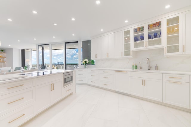 100 Lakeshore Dr Unit 1954, North Palm Beach, FL 33408 - kitchen featuring a sink, stainless steel microwave, decorative backsplash, light countertops, and white cabinets