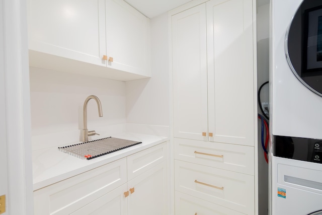 100 Lakeshore Dr Unit 1954, North Palm Beach, FL 33408 - kitchen with estacked washer and dryer, white cabinets, light countertops, and a sink