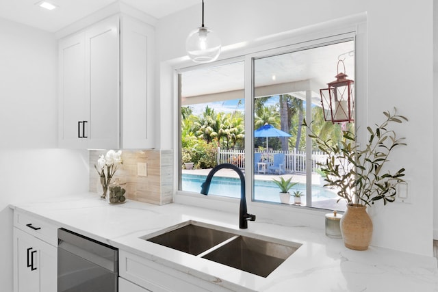 4060 Lake Dr, Coconut Creek, FL 33066 - kitchen with a sink, stainless steel dishwasher, backsplash, white cabinetry, and light stone countertops