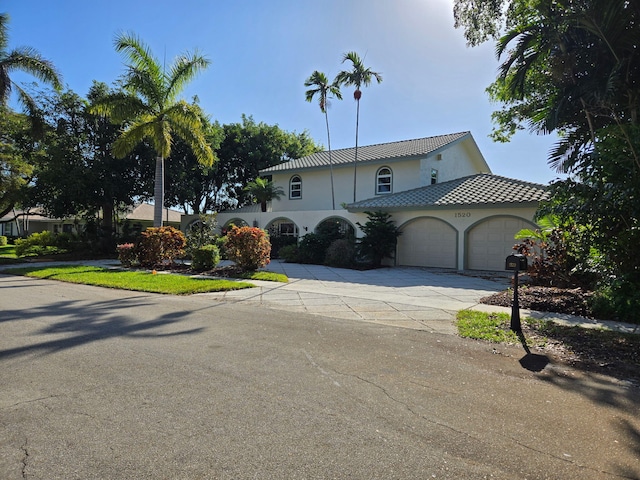 mediterranean / spanish home featuring an attached garage, concrete driveway, and stucco siding