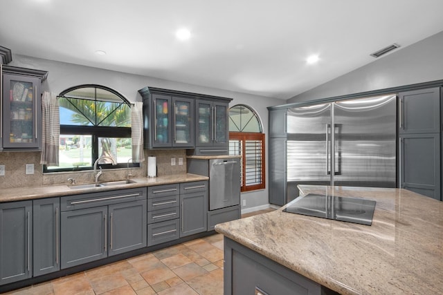 kitchen featuring stainless steel built in refrigerator, a sink, wall oven, black electric stovetop, and tasteful backsplash