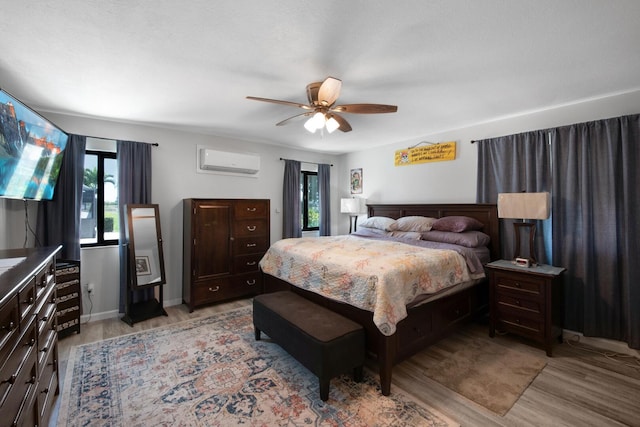 bedroom with a wall unit AC, light wood finished floors, and multiple windows
