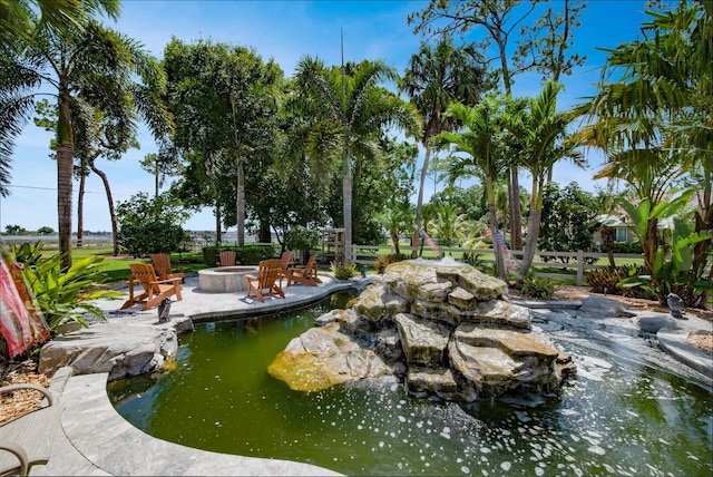 surrounding community featuring an outdoor fire pit, a garden pond, and a patio