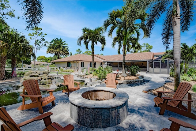 view of patio / terrace featuring an outdoor fire pit and a sunroom