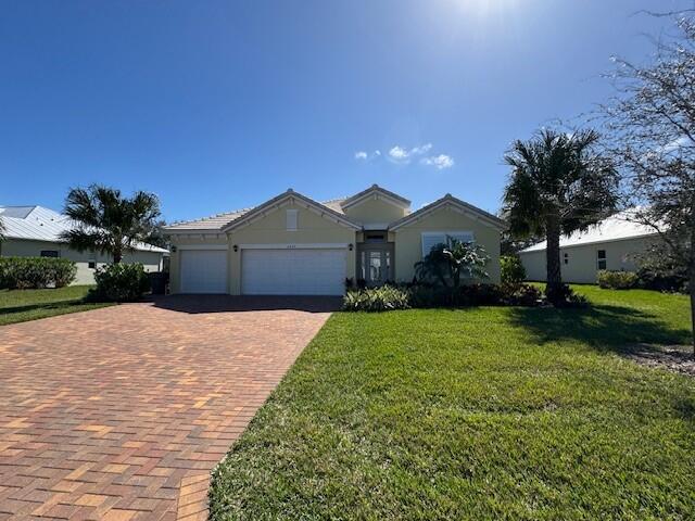 2557 Saint Lucia Cir, Vero Beach, FL 32967 - ranch-style house featuring decorative driveway, an attached garage, and a front yard