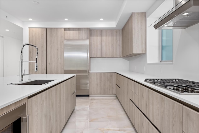 475 E Royal Palm Rd Unit 205, Boca Raton, FL 33432 - kitchen with wall chimney range hood, stainless steel appliances, light brown cabinetry, a sink, and modern cabinets