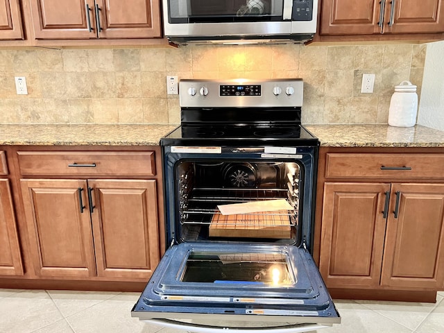kitchen with stainless steel appliances, light tile patterned flooring, and tasteful backsplash