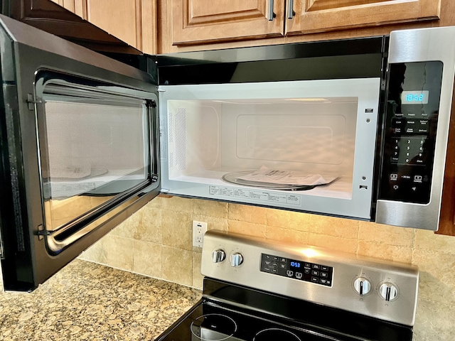 kitchen view of stainless steel electric range oven and backsplash