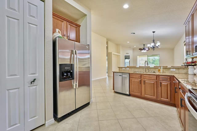kitchen with stainless steel appliances, a sink, a chandelier, a peninsula, and light stone counters