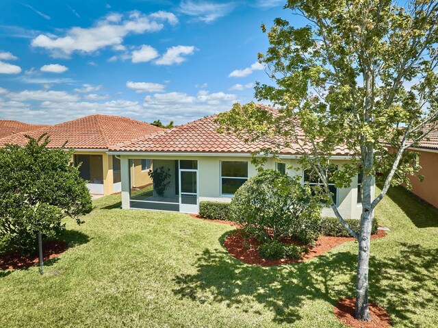 back of property featuring a tile roof, stucco siding, a yard, and a sunroom