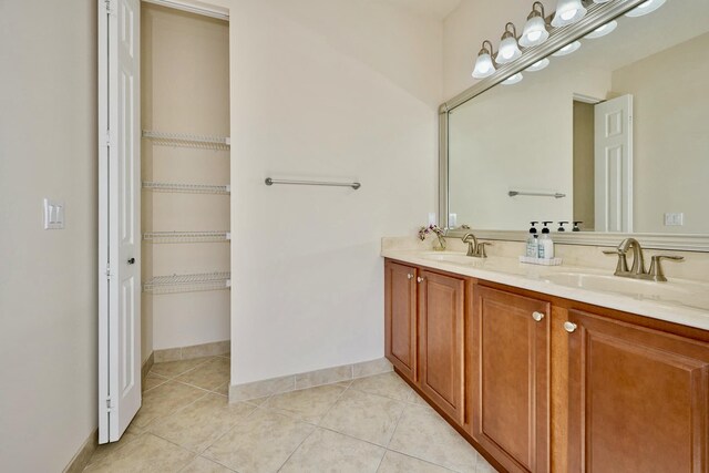 bathroom featuring tile patterned floors, double vanity, and baseboards