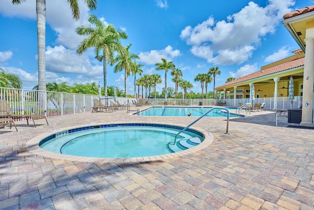 community pool with fence, a ceiling fan, and a patio area