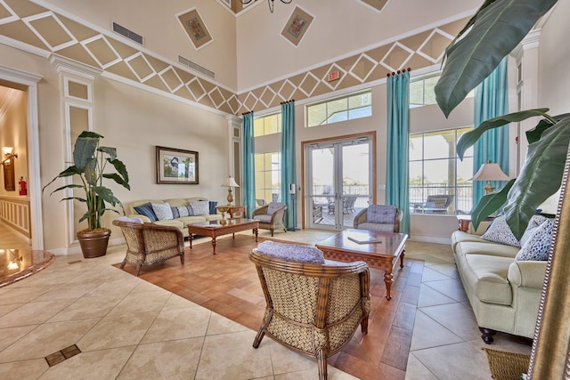 tiled living room with a high ceiling, ornate columns, french doors, ornamental molding, and baseboards
