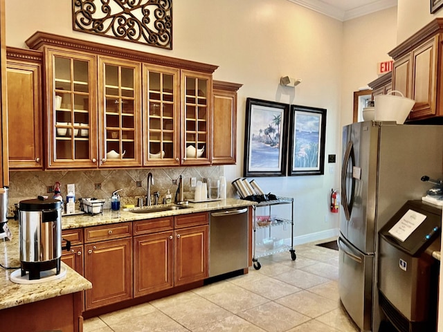 kitchen featuring appliances with stainless steel finishes, a sink, decorative backsplash, light tile patterned flooring, and crown molding