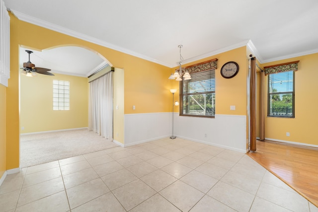 unfurnished room with a chandelier, crown molding, light tile patterned flooring, arched walkways, and ceiling fan