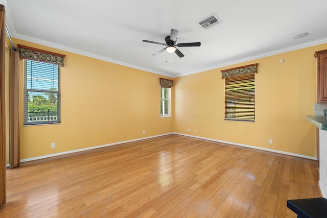 spare room featuring healthy amount of natural light, a ceiling fan, baseboards, light wood-style floors, and ornamental molding