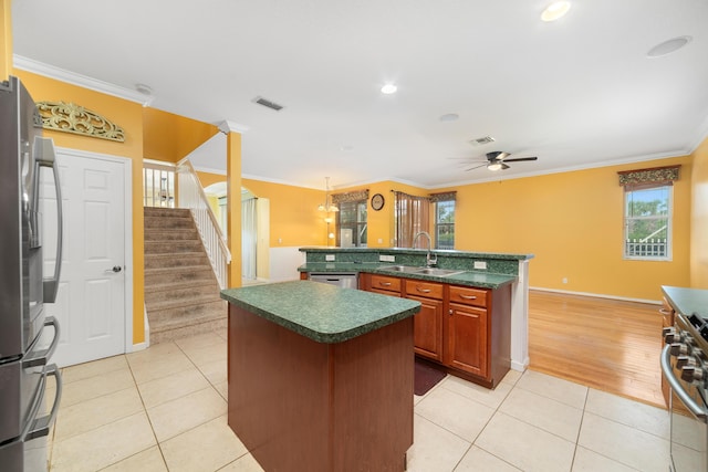kitchen featuring an island with sink, a sink, crown molding, dark countertops, and light tile patterned floors