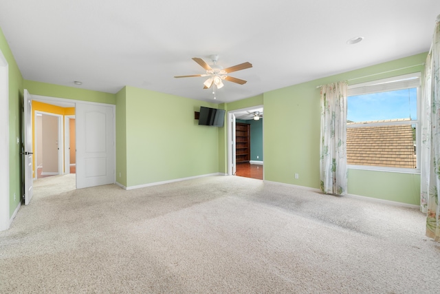 carpeted empty room featuring a ceiling fan and baseboards