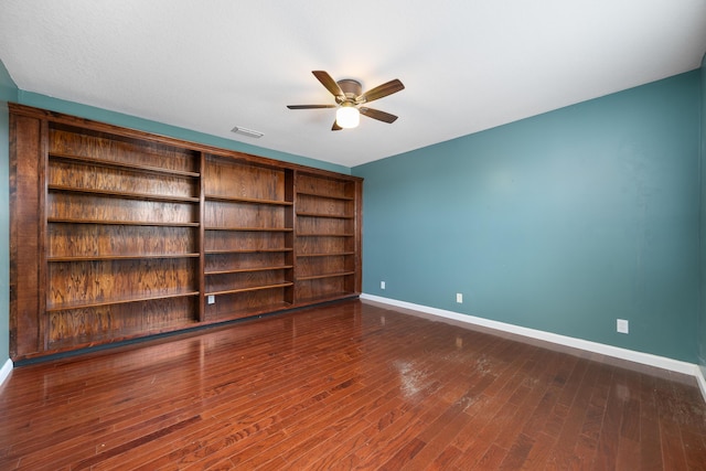 spare room featuring baseboards, a ceiling fan, and dark wood-style floors