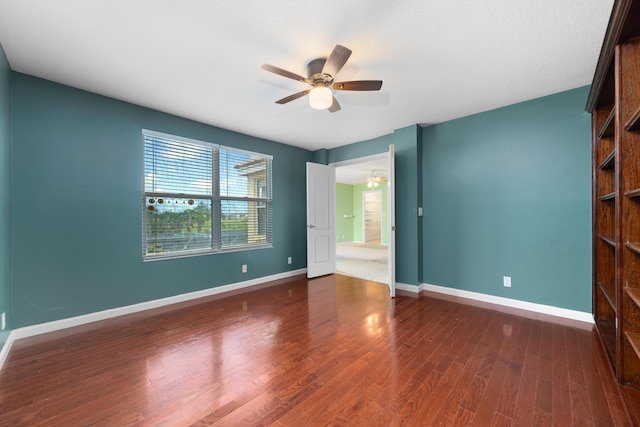 empty room featuring a ceiling fan, baseboards, and wood finished floors
