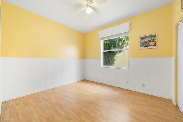 spare room with wainscoting, wood finished floors, and a ceiling fan