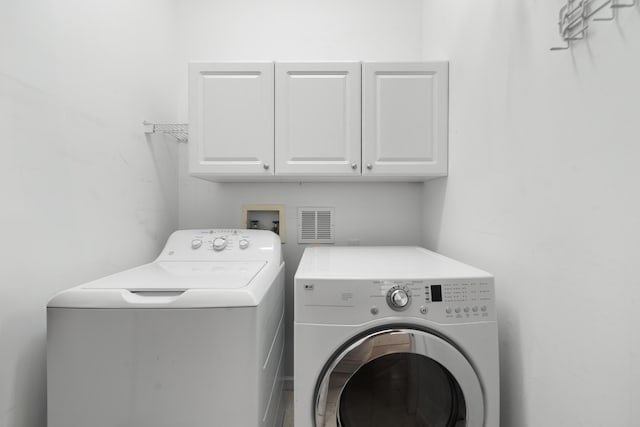 washroom with cabinet space and washing machine and clothes dryer