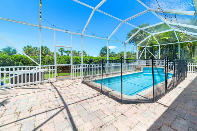 view of swimming pool featuring a patio, a lanai, and fence