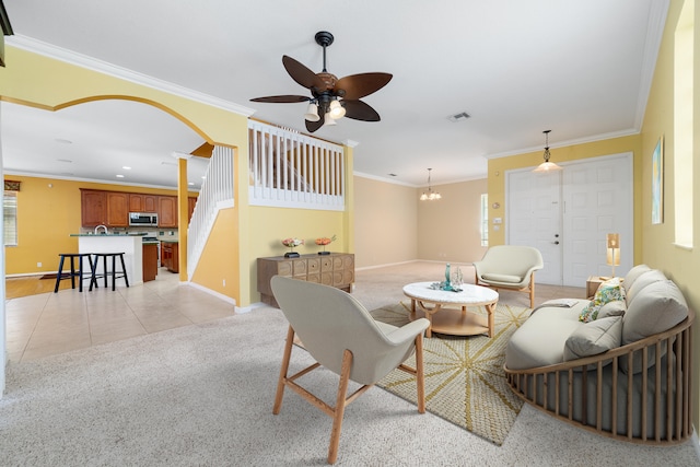 living room featuring baseboards, a ceiling fan, crown molding, light tile patterned flooring, and a chandelier