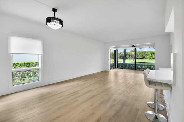 7884 Seville Pl Unit 1301, Boca Raton, FL 33433 - unfurnished living room with light wood finished floors, a chandelier, baseboards, and ceiling fan
