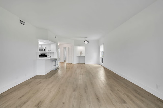 7884 Seville Pl Unit 1301, Boca Raton, FL 33433 - unfurnished living room with light wood-style flooring, baseboards, and a sink