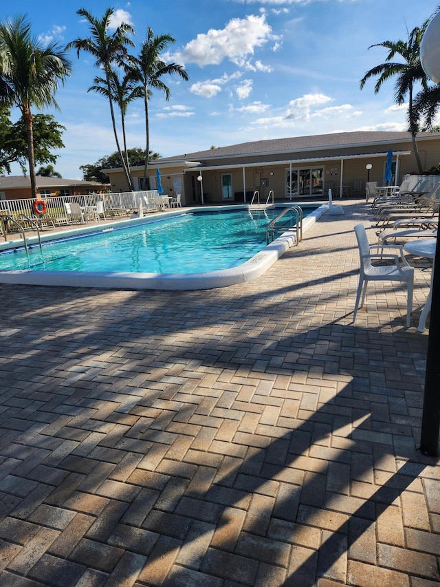 community pool with a patio area and fence