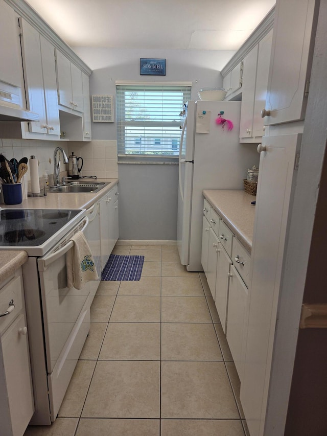 kitchen with white appliances, a sink, under cabinet range hood, light countertops, and backsplash