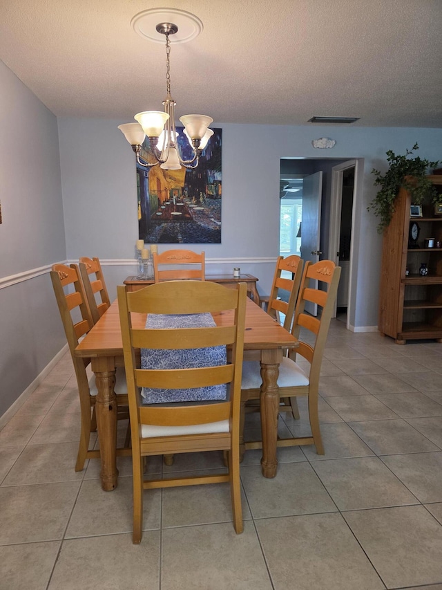 tiled dining space featuring a chandelier, a textured ceiling, and baseboards