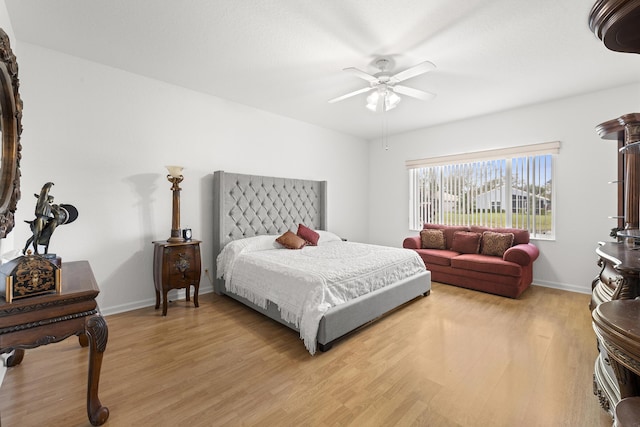 bedroom with light wood-type flooring, a ceiling fan, and baseboards