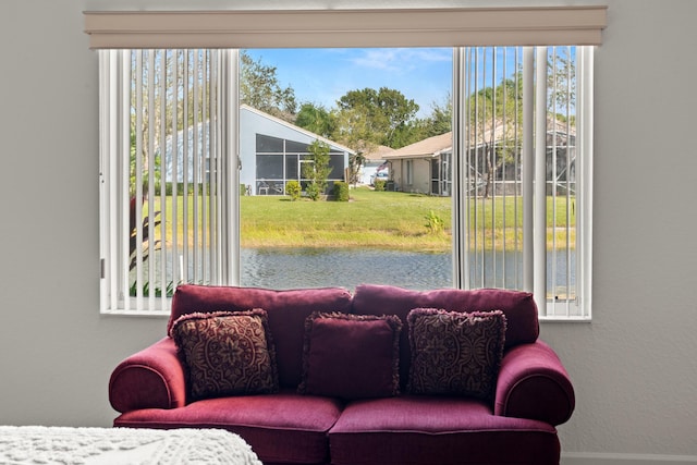 living area featuring plenty of natural light, a water view, and baseboards