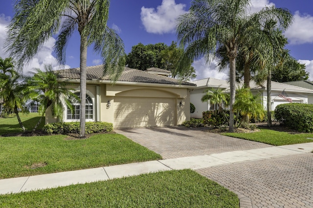 view of front of home with decorative driveway, an attached garage, stucco siding, a front yard, and a tile roof