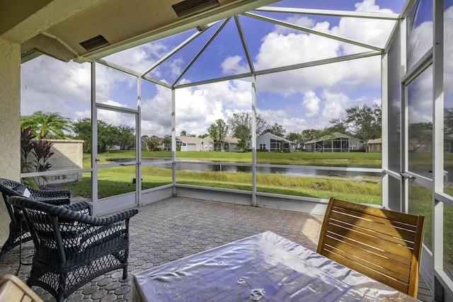 sunroom / solarium featuring a water view and a residential view