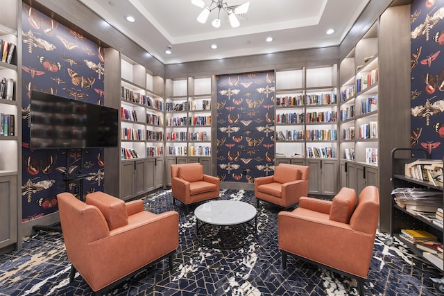 living area featuring built in features, bookshelves, a tray ceiling, and recessed lighting