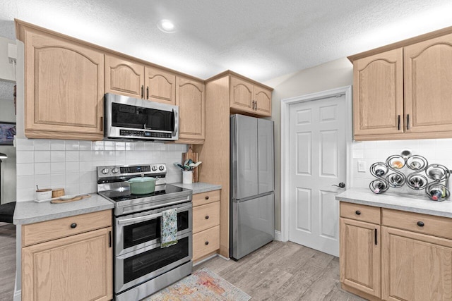 639 Mallard Dr, Delray Beach, FL 33444 - kitchen with stainless steel appliances, light brown cabinetry, light wood-type flooring, tasteful backsplash, and a textured ceiling