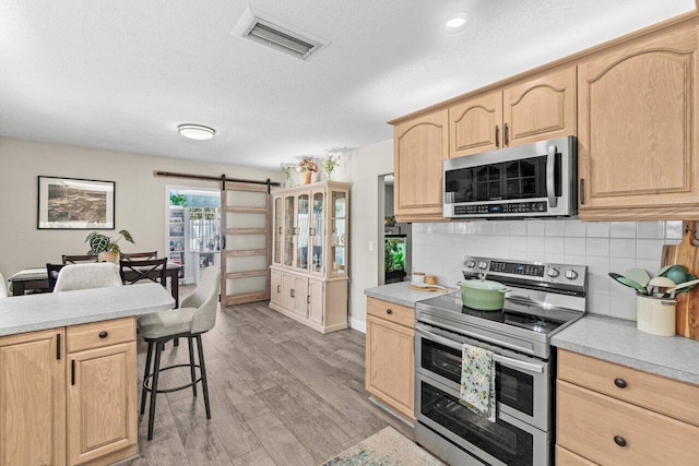 639 Mallard Dr, Delray Beach, FL 33444 - kitchen featuring stainless steel appliances, light brown cabinetry, light countertops, and a textured ceiling