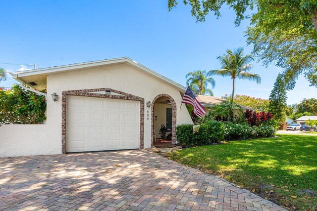 639 Mallard Dr, Delray Beach, FL 33444 - mediterranean / spanish house featuring stucco siding, a front lawn, an attached garage, and decorative driveway