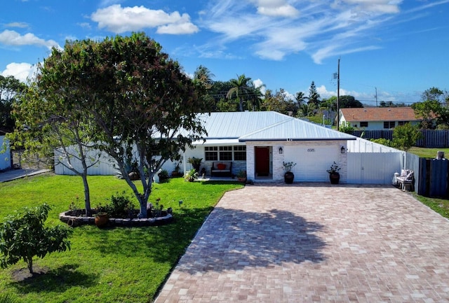 ranch-style house with decorative driveway, an attached garage, metal roof, and stone siding