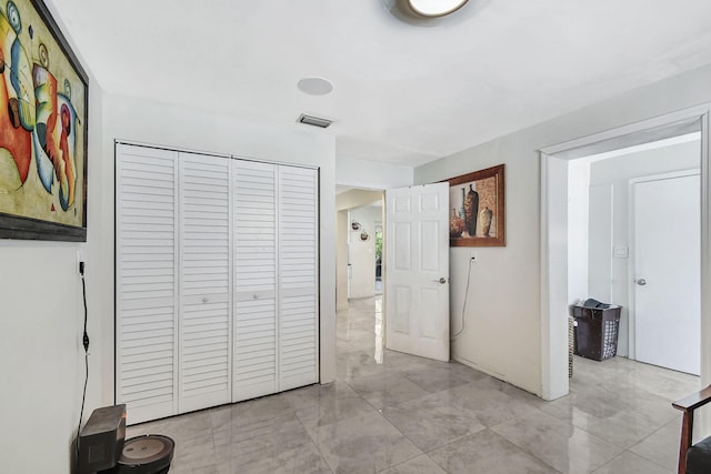 unfurnished bedroom with a closet and light marble finish flooring