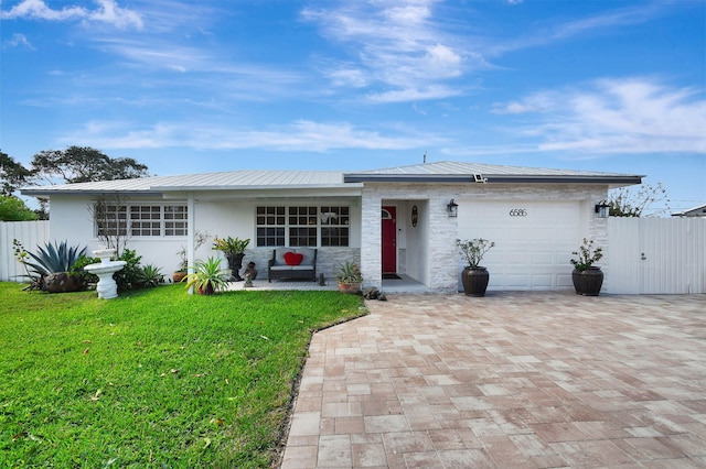ranch-style house with decorative driveway, a garage, metal roof, stucco siding, and a gate