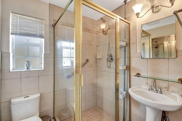 full bath with tile walls, a shower stall, a sink, and toilet