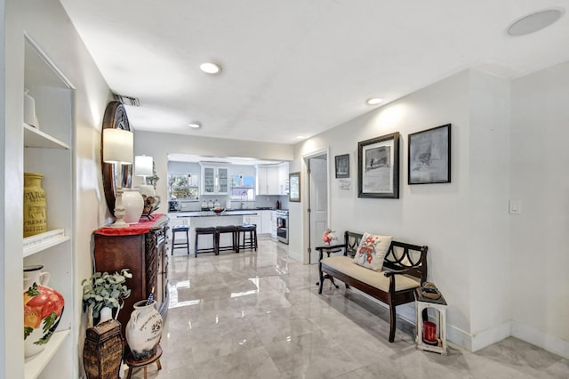 corridor with light marble finish floors, recessed lighting, and baseboards