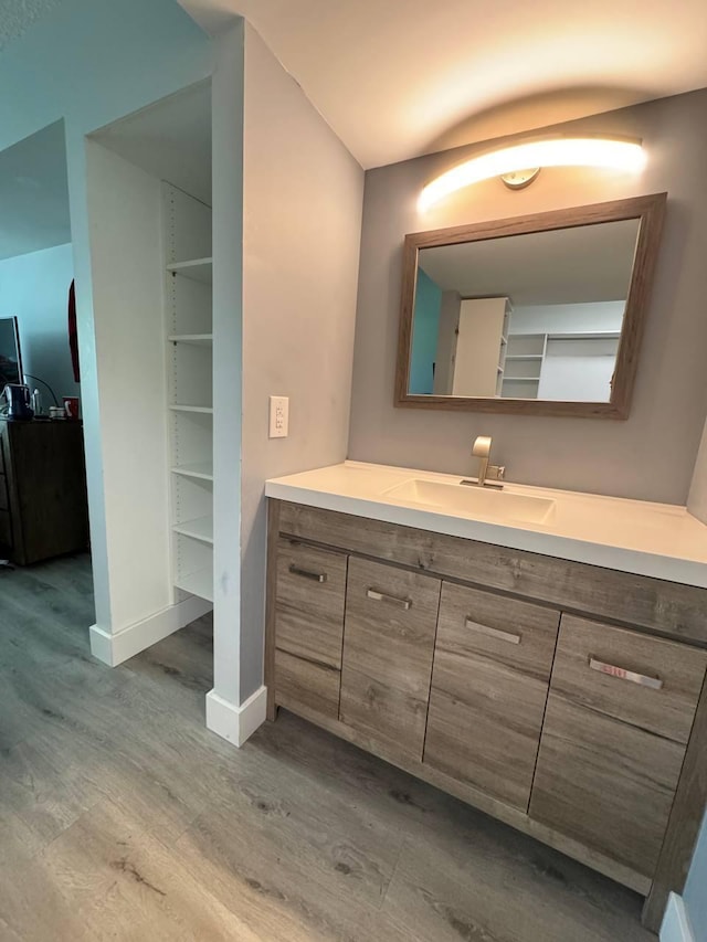 bathroom with wood finished floors, vanity, and baseboards