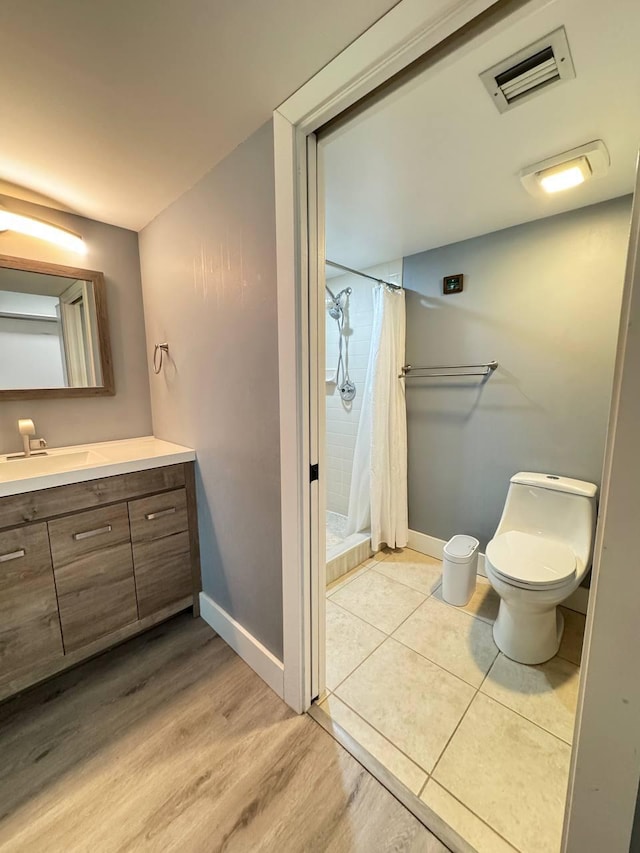 full bathroom featuring a shower stall, vanity, toilet, baseboards, and wood finished floors