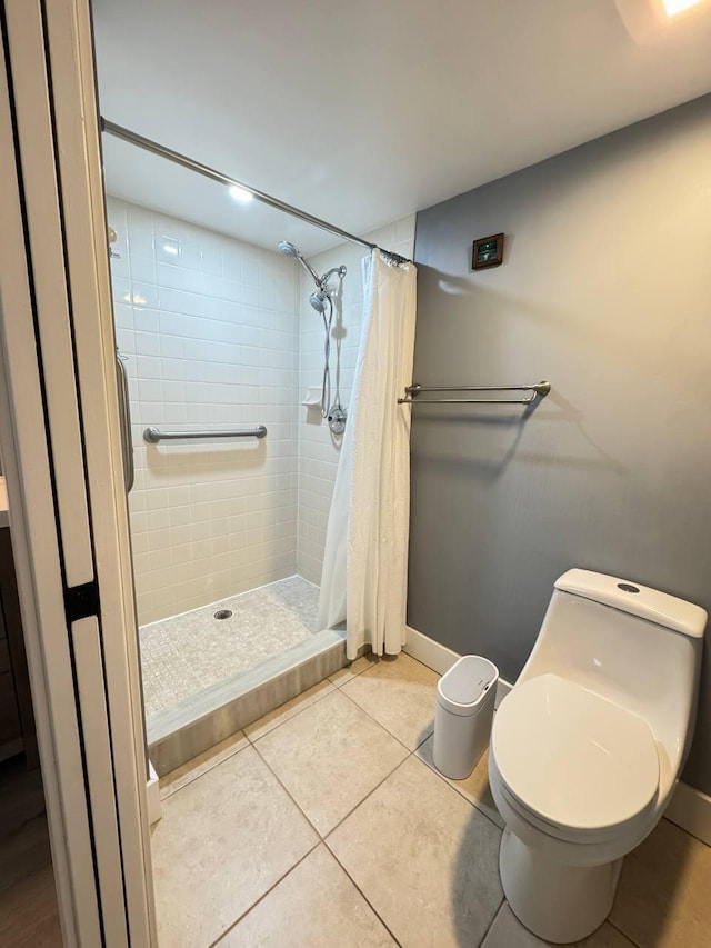 bathroom with a shower stall, baseboards, toilet, and tile patterned flooring