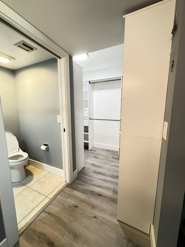 bathroom with toilet, wood finished floors, and baseboards